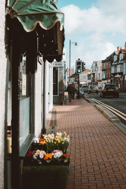 A close-up view of a colorful flower display outside a florist shop on Ardleigh Green Road, Emerson Park. The arrangement includes vibrant yellow, white, pink, and purple flowers, such as daisies and 